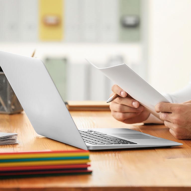 Man Holding papers with Laptop